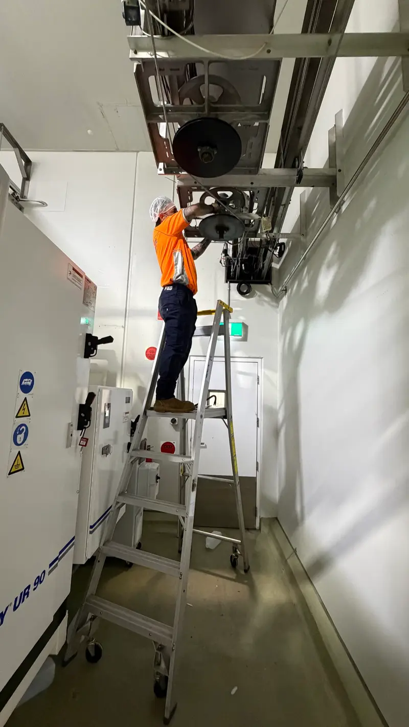 Technician servicing overhead industrial equipment on-site